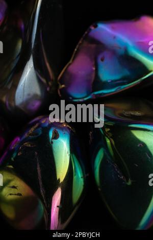 Gros plan des cailloux brillants endommagés recouverts d'un revêtement arc-en-ciel sur du noir arrière-plan Banque D'Images