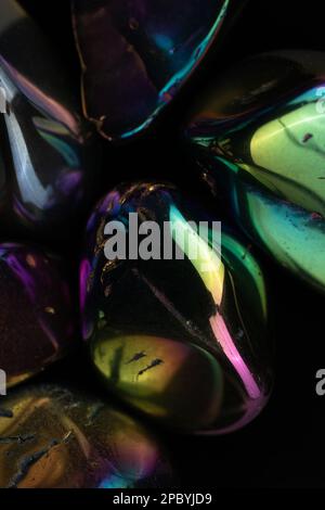 Gros plan des cailloux brillants endommagés recouverts d'un revêtement arc-en-ciel sur du noir arrière-plan Banque D'Images