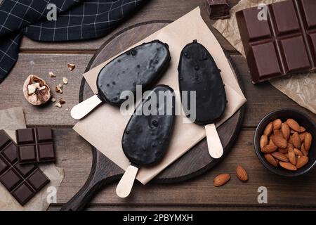 Délicieuses glaces glacées, chocolat et noix sur table en bois, plat Banque D'Images