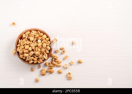 Grains de cacahuètes aromatisés épicés dans un bol sur fond de table blanc. Banque D'Images