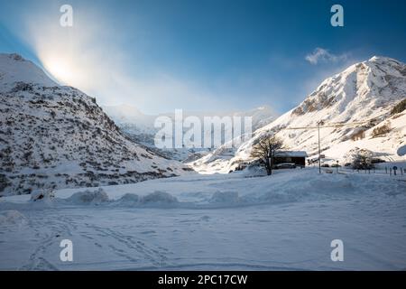 Alpes enneigées à Tschamut, Suisse. Chaîne de montagnes, vue grand angle, ciel bleu, coucher de soleil derrière la montagne, personne. Banque D'Images
