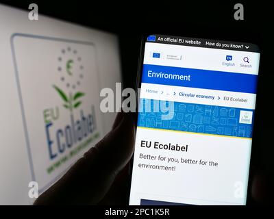 Personne tenant un téléphone portable avec un site Internet de certification environnementale écolabel européen à l'écran devant le logo. Concentrez-vous sur le centre de l'écran du téléphone. Banque D'Images