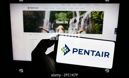 Personne tenant un smartphone avec le logo de la société de traitement de l'eau Pentair plc à l'écran devant le site Web. Mise au point sur l'affichage du téléphone. Banque D'Images