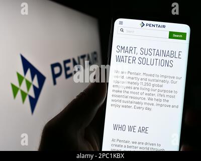 Personne tenant un téléphone portable avec la page web de la société de traitement de l'eau Pentair plc sur l'écran devant le logo. Concentrez-vous sur le centre de l'écran du téléphone. Banque D'Images