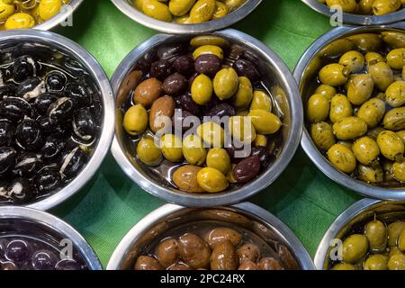 Diverses olives cuites dans des bols en métal à la vue sur le marché. Banque D'Images