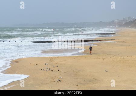 Boscombe, Bournemouth, Dorset, Royaume-Uni, 13th mars 2023, Météo. Vents violents et tempête sur le front de mer le matin. Un coureur solitaire sur la plage. Crédit : Paul Biggins/Alamy Live News Banque D'Images