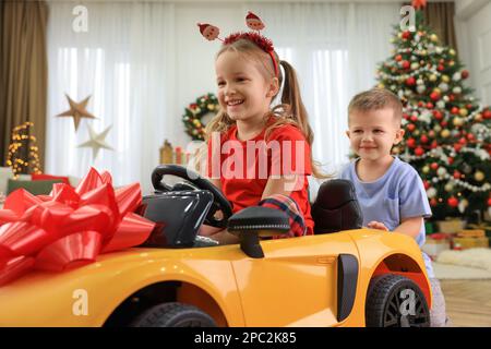 Mignon petit garçon poussant la voiture jouet avec sa sœur dans la chambre décorée pour Noël Banque D'Images
