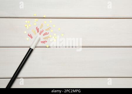 Magnifique baguette magique noire et confetti sur table en bois blanc, plat. Espace pour le texte Banque D'Images