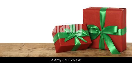 Boîtes-cadeaux rouges avec noeuds verts sur table en bois sur fond blanc, espace pour le texte Banque D'Images