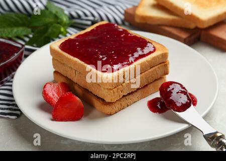 Toasts servis avec de la confiture savoureuse et des fraises sur une table légère, en gros plan Banque D'Images