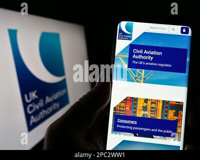 Personne tenant un téléphone portable avec le site Web de l'autorité de réglementation britannique de l'aviation civile (CAA) à l'écran avec le logo. Concentrez-vous sur le centre de l'écran du téléphone. Banque D'Images