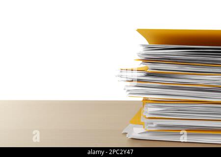 Pile de fichiers jaunes avec des documents sur une table en bois sur fond blanc. Espace pour le texte Banque D'Images