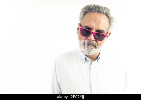 Drôle d'homme à poil gris portant des lunettes roses dans une chemise classique blanche isolée sur un fond blanc. Photo de haute qualité Banque D'Images