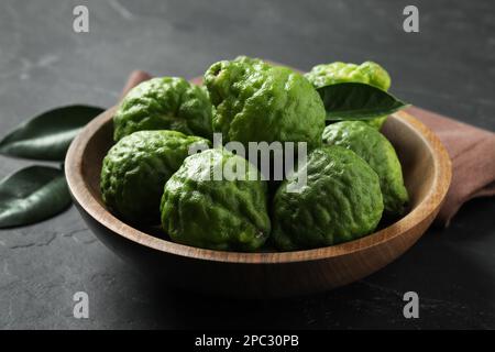 Fruits de bergamote mûrs frais dans un bol sur une table noire Banque D'Images