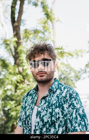 Portrait du jeune homme en lunettes de soleil debout dans le parc d'été, image de stock Banque D'Images