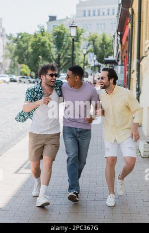 Amis interraciaux positifs parlant en marchant sur andrews descente à Kiev, image de stock Banque D'Images