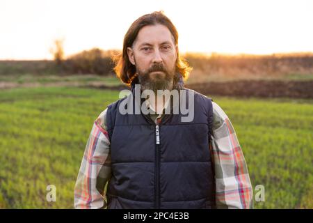 Portrait d'un fermier barbu sur un champ au coucher du soleil. Banque D'Images