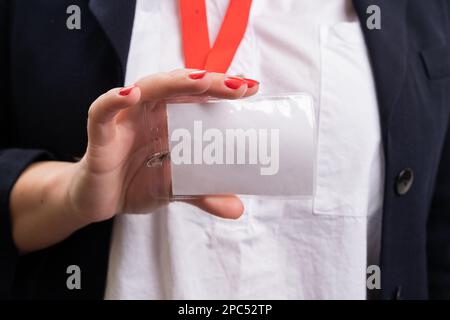 Gros plan d'une femme d'affaires en tenue de tenue présentant vide badge d'étiquette de nom comme espace de copie vierge isolé sur fond blanc de studio Banque D'Images
