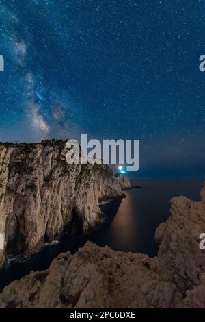 Milky Way et phare sur le sommet de la montagne à la nuit étoilée en été. Magnifique paysage avec des falaises, côte rocheuse de mer, ciel avec la voie laiteuse lumineuse a Banque D'Images