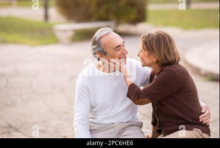 Couple sénior amoureux ayant une date romantique se tenant assis dans le parc Banque D'Images