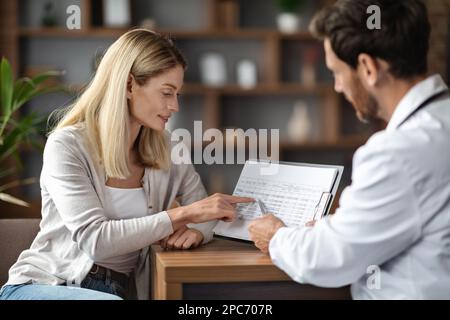 Femme discutant des résultats des analyses sanguines avec le médecin pendant la réunion au bureau Banque D'Images