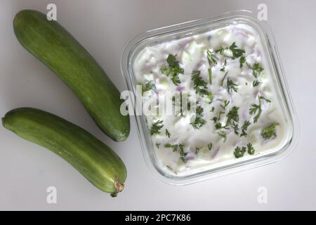 Raita de concombre. Concombre et oignons finement hachés dans un yaourt épais épicé avec des piments verts et garni de feuilles de coriandre. Accompagnement recette de plat avec Banque D'Images