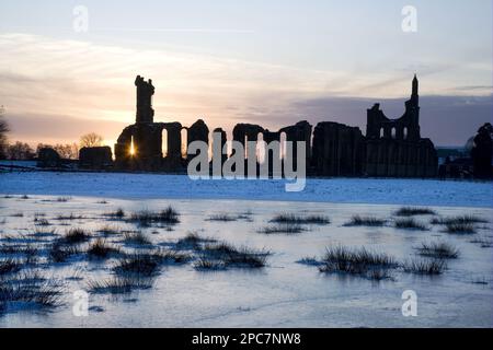 Ruines de l'abbaye silhouetée au coucher du soleil, marais gelé en premier plan, Abbaye de Byland, près de Helmsley, Yorkshire du Nord, Angleterre, Royaume-Uni Banque D'Images