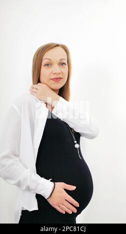 portrait d'une jeune femme enceinte sur fond blanc. garde ses mains sur son estomac ballonné. Concept d'amour. Horizontale avec espace de copie Banque D'Images