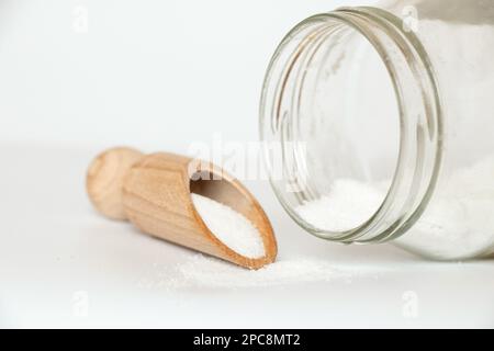 Sel comestible dans une cuillère en bois et un pot en verre à côté sur fond blanc gros plan Banque D'Images