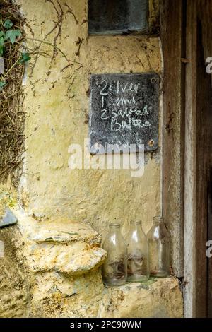 Trois bouteilles de lait vides laissées à l'extérieur d'une maison pour être recueillies par le milkman. Au-dessus des bouteilles un tableau noir montre une demande de lait pour le milkman Banque D'Images