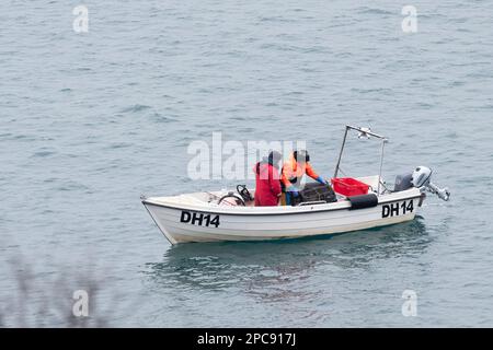 Deux pêcheurs dans un petit bateau transportent à bord d'un pot de homard ou d'un piège à homard de la mer après qu'il ait été laissé à l'endroit plus tôt dans la journée Banque D'Images