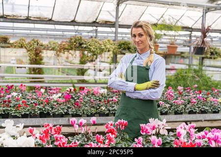 Portrait d'une femme heureuse travaillant à l'intérieur d'une serre ou d'un centre de jardin Banque D'Images