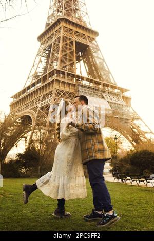 Un couple embrassant devant la Tour Eiffel à Paris. Voyage romantique, lune de miel en Europe. France ville d'amour. Banque D'Images