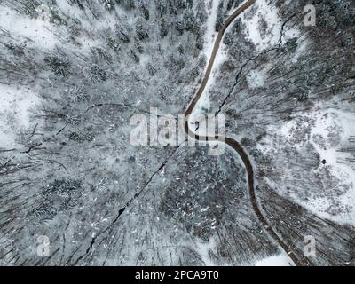 Vue en hauteur avec un drone d'une belle neige couverte nature d'hiver avec forêt et une route qui se courbe. Banque D'Images