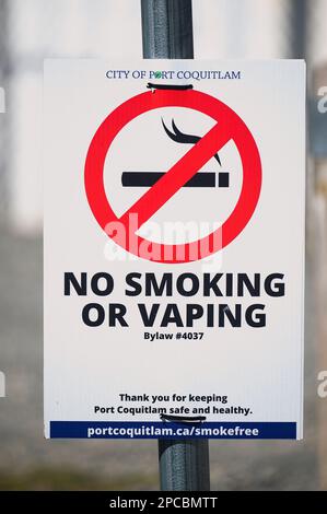 Panneau interdiction de fumer ou de sauter avec symbole rouge cercle-barre oblique sur une cigarette allumée montée sur un poteau lumineux. Port Coquitlam, B. C., Canada - vertical. Banque D'Images