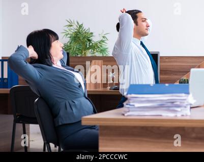 Les deux employés qui font des exercices de sport au bureau Banque D'Images