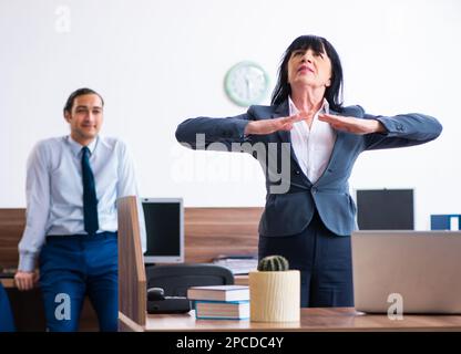 Les deux employés qui font des exercices de sport au bureau Banque D'Images