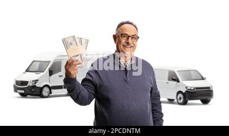 Homme mature tenant des piles d'argent devant deux fourgonnettes blanches et souriant isolé sur fond blanc Banque D'Images