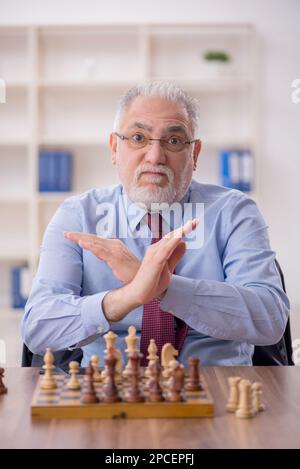 Un vieil employé de sexe masculin joue aux échecs dans le bureau Banque D'Images