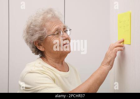Femme âgée regardant la note de rappel à l'intérieur. Perte de mémoire liée à l'âge Banque D'Images