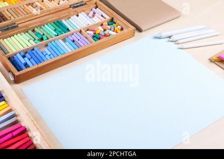 Papier vierge, pastels doux et crayons à dessin sur une table en bois sur le lieu de travail de l'artiste. Espace de conception Banque D'Images