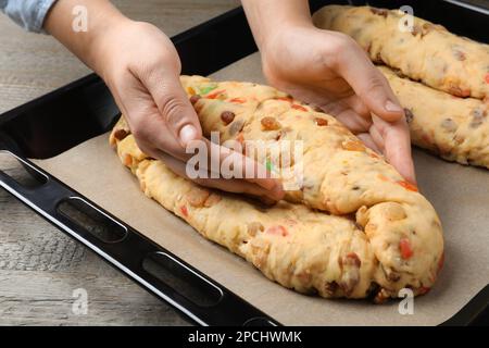 Femme faisant Stollen avec des fruits confits et des noix sur la plaque de cuisson à table en bois, gros plan. Pain de Noël traditionnel allemand Banque D'Images