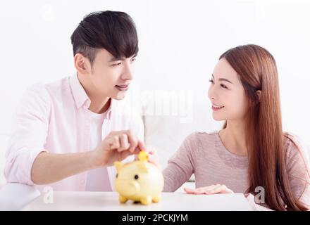 Un jeune couple asiatique tient à Piggybank et fait des économies pour l'avenir Banque D'Images