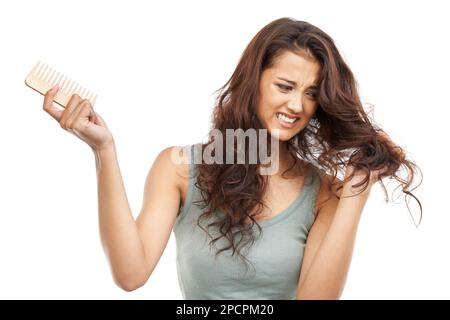 Problèmes de cheveux. Une femme qui se bat avec ses cheveux tenant un peigne. Banque D'Images