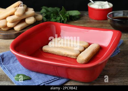 Bol avec délicieux biscuits savoiardi pour tiramisu sur table en bois Banque D'Images
