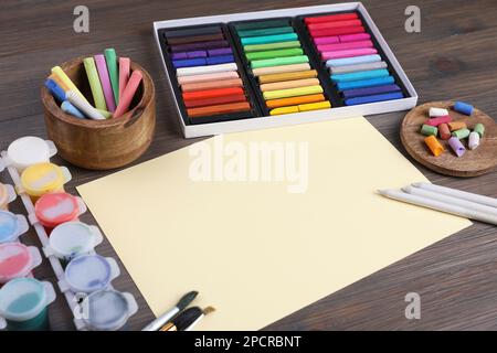 Feuille de papier vierge, pastels à la craie colorés et autres outils de dessin sur table en bois. Le lieu de travail de l'artiste moderne Banque D'Images