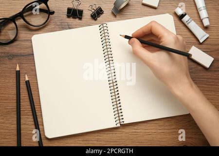 Femme avec un crayon et un carnet d'esquisses vierge à une table en bois, vue de dessus Banque D'Images