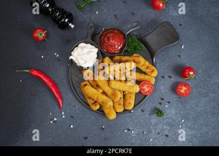 Bâtonnets de fromage Mozzarella cuits avec sauce tartare et tomate rouge sur une assiette Banque D'Images