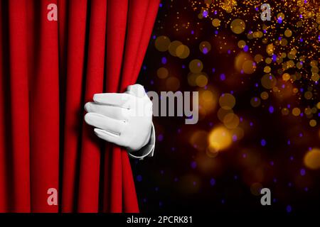 Homme ouvrant le rideau avant rouge contre les lumières floues. Effet bokeh Banque D'Images