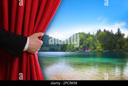 Homme ouvrant le rideau rouge avant et vue pittoresque sur la rivière et les montagnes sur fond Banque D'Images